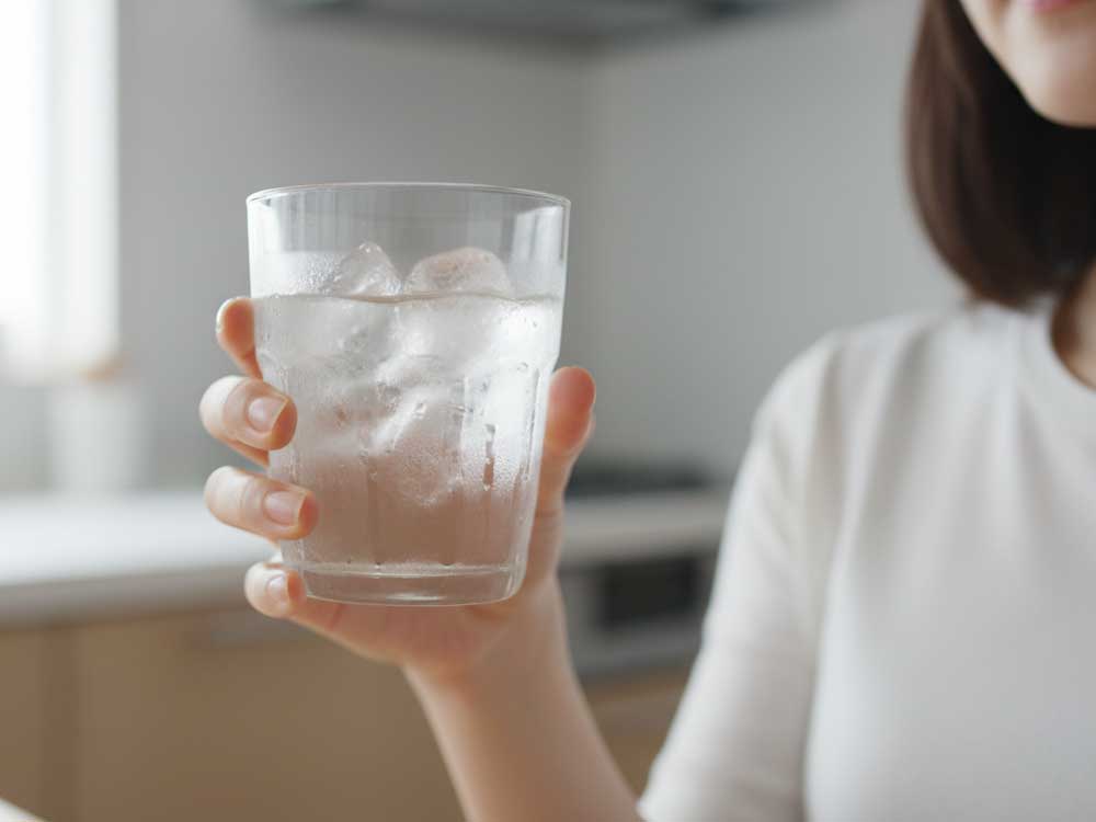 冷たい水が入ったコップを持っている女性