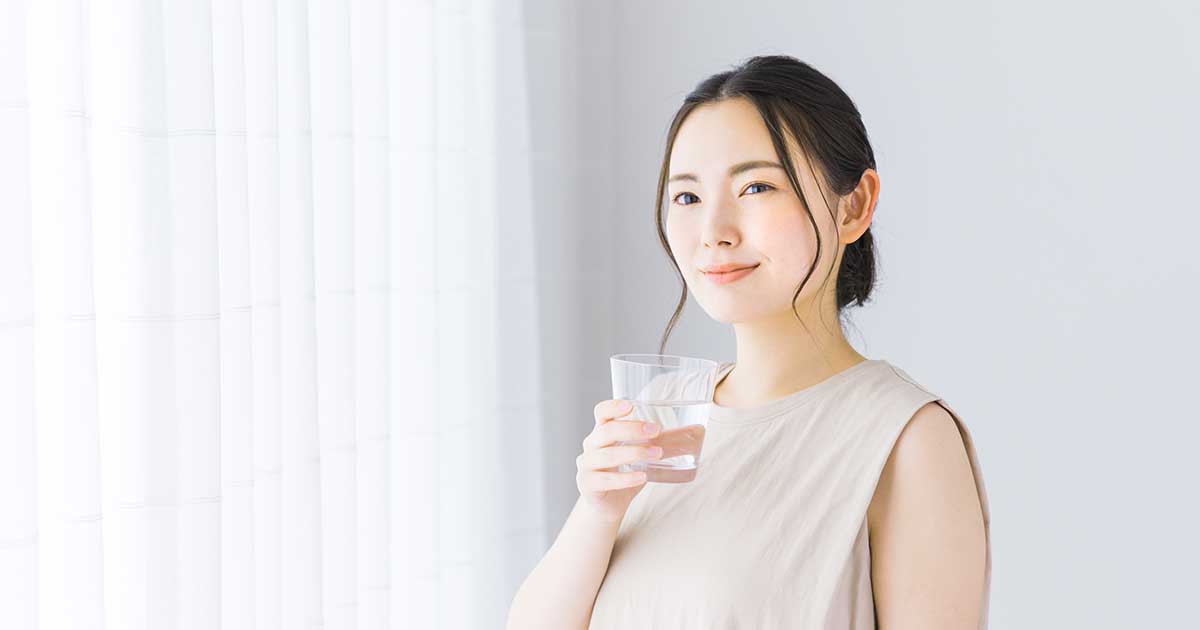 明るい室内で女性がお悩み水を飲む