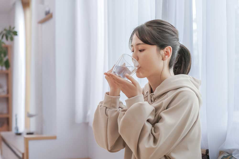 グラスからこまめに水分補給をおこなう女性のイメージ